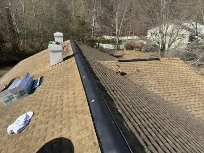 Ridge vent installation on tan asphalt shingle roof in King of Prussia, PA, showing roofing materials and attic ventilation pipes for improved home ventilation and energy efficiency.