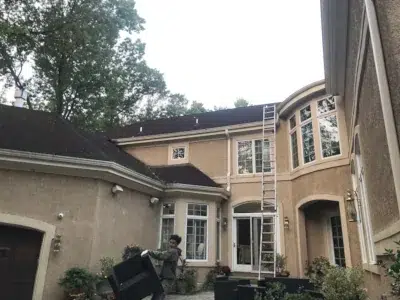 Ladders being set up and outdoor furniture moved at the start of a residential roof replacement by XL Home Improvements.