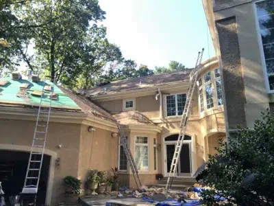 Halfway through shingle roof replacement on a large home, with most shingles installed and work shifting to the garage.