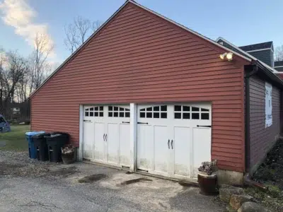 Closeup view of a worn-out garage siding on a residential property in Berwyn, PA before replacement by XL Home Improvements.