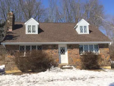 roof and gutter replacement completed by XL Home Improvements in Schwenksville PA on stone home with dormers