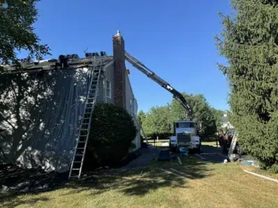 Roofing project in progress in Collegeville PA with crew working and truck-mounted equipment in use